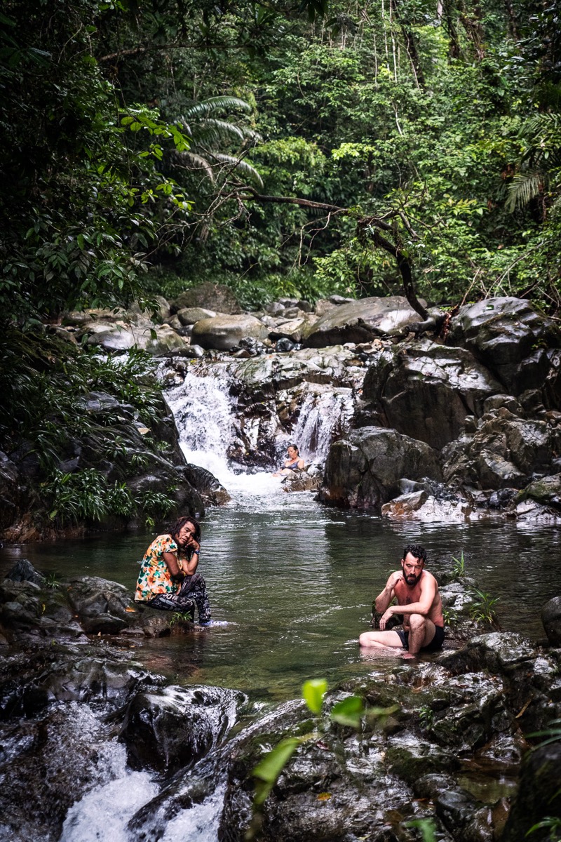 Guests swimming at a rainforest waterfall
